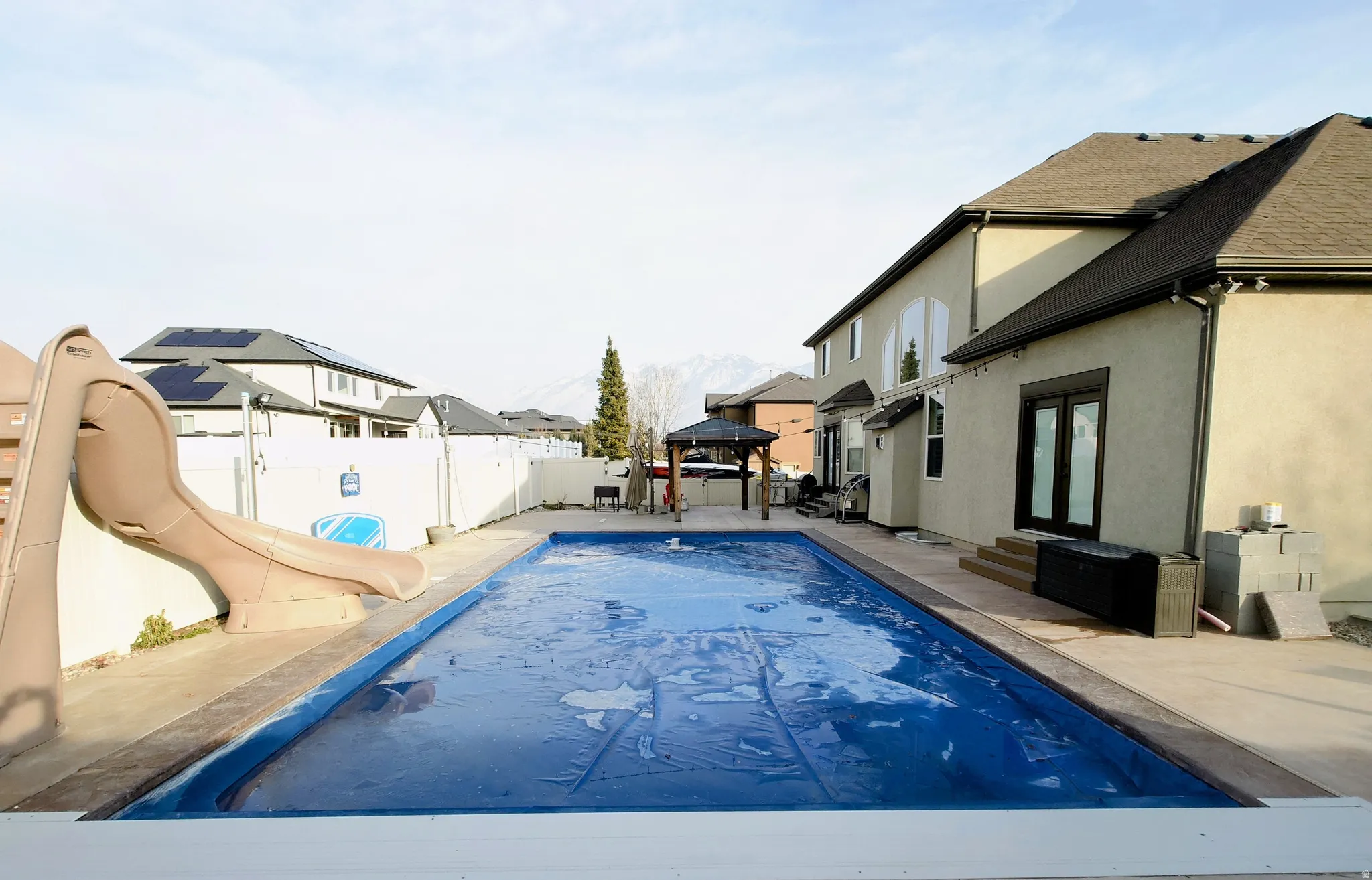 View of swimming pool featuring a gazebo, a water slide, a fenced backyard, a patio area, and entry steps