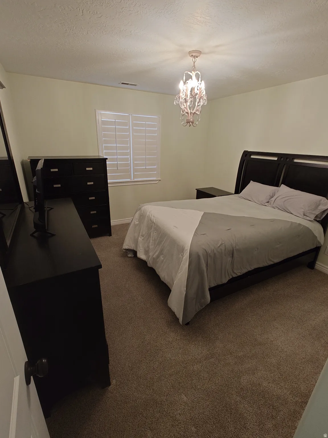 Bedroom with dark carpet, a textured ceiling, and a chandelier