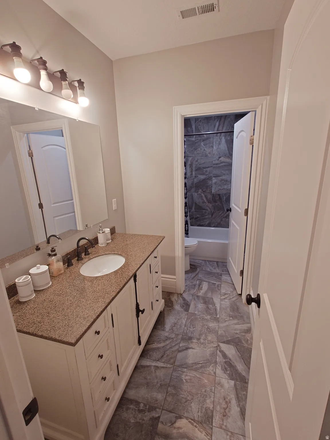 Bathroom featuring vanity and shower / bathtub combination with curtain