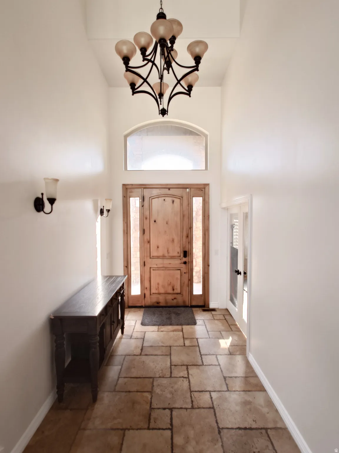 Entryway featuring a chandelier, a high ceiling, french doors, and stone tile flooring