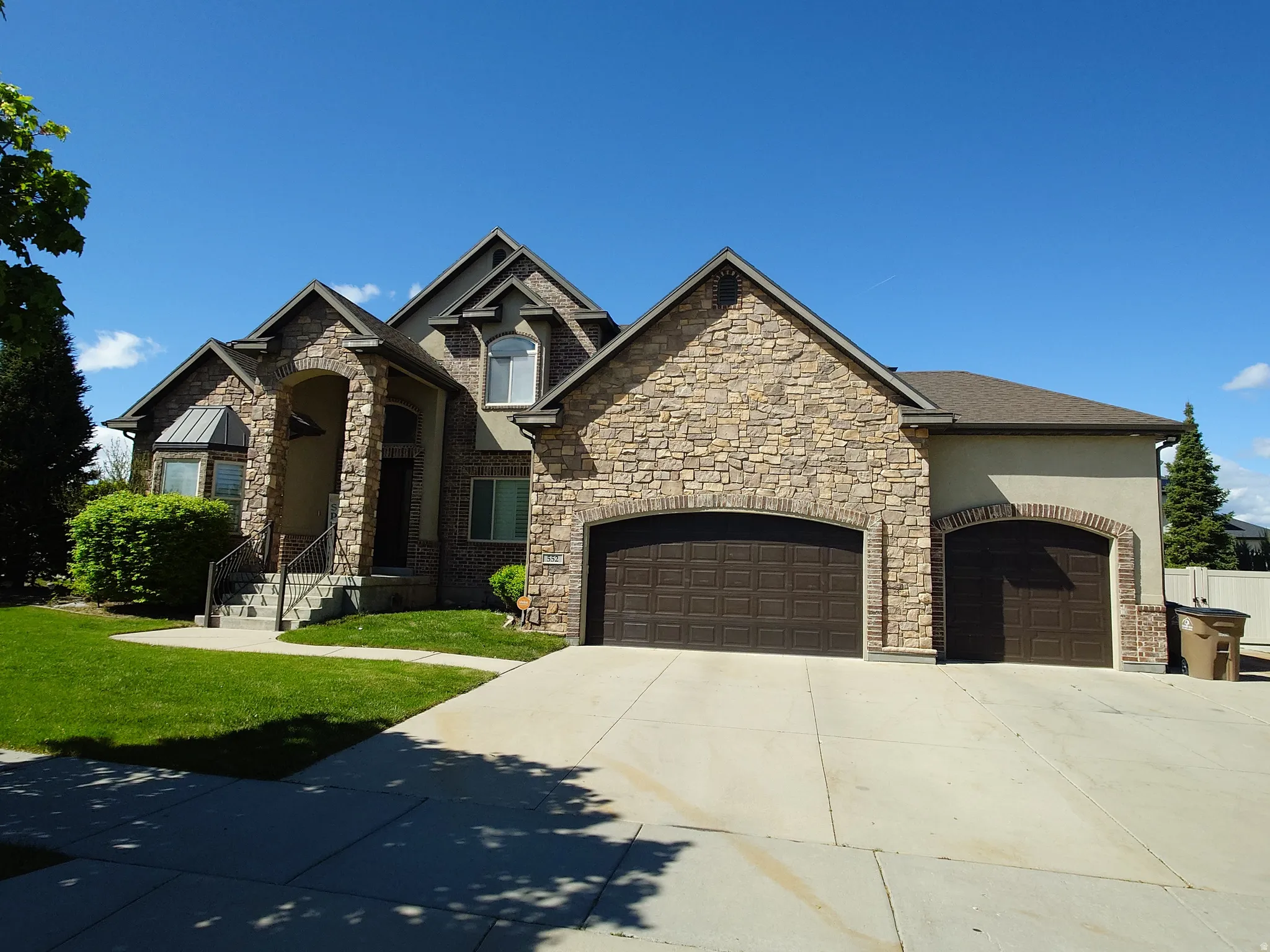 Craftsman inspired home with a garage, stone siding, concrete driveway, a front lawn, and stucco siding