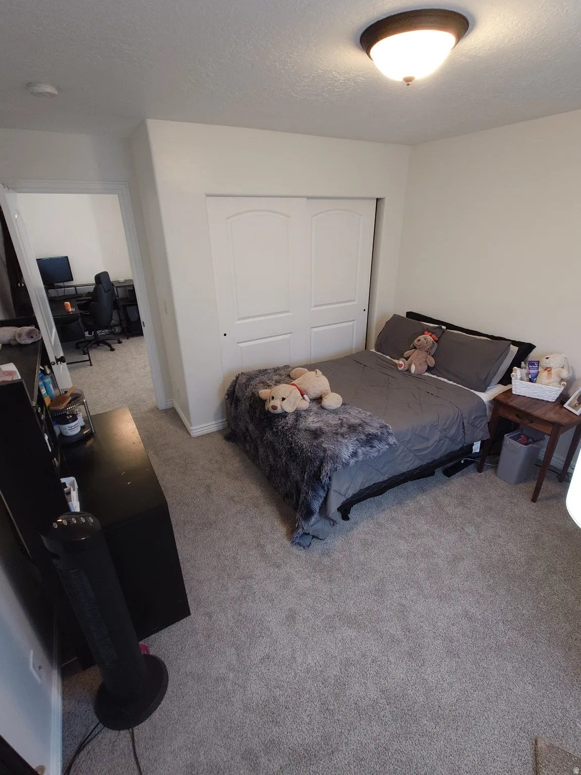 Bedroom with a desk, a closet, carpet flooring, and a textured ceiling