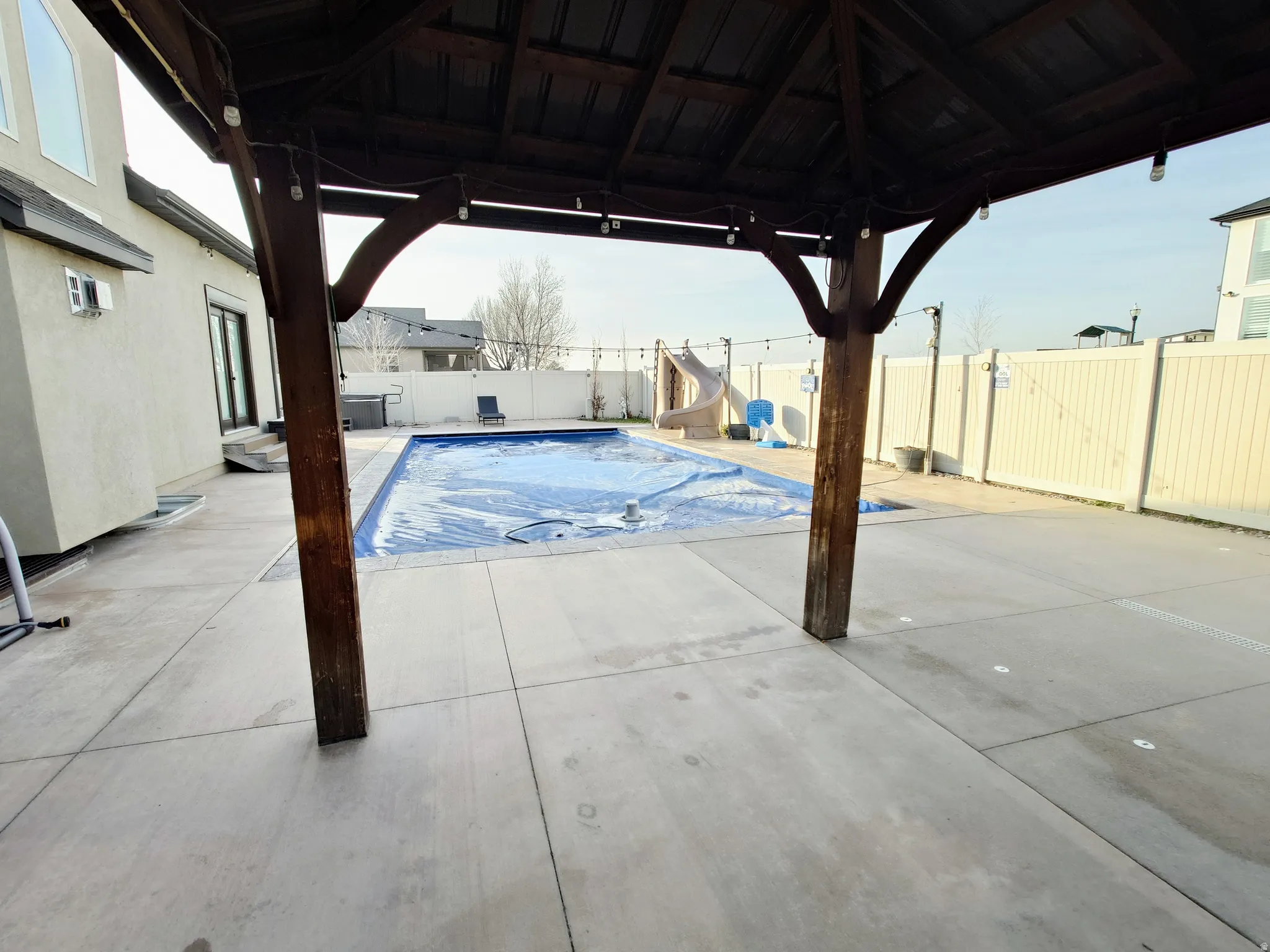 View of swimming pool with a water slide, a gazebo, a patio, and a fenced backyard