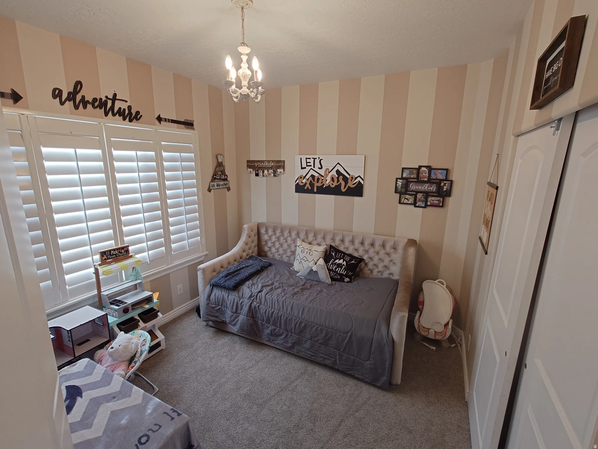Bedroom featuring carpet floors, wallpapered walls, a chandelier, and a textured ceiling