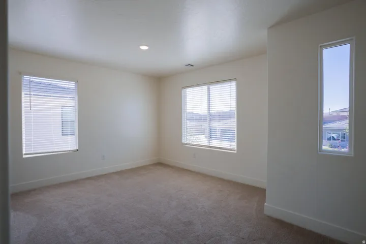 Spare room featuring light colored carpet, plenty of natural light, and recessed lighting