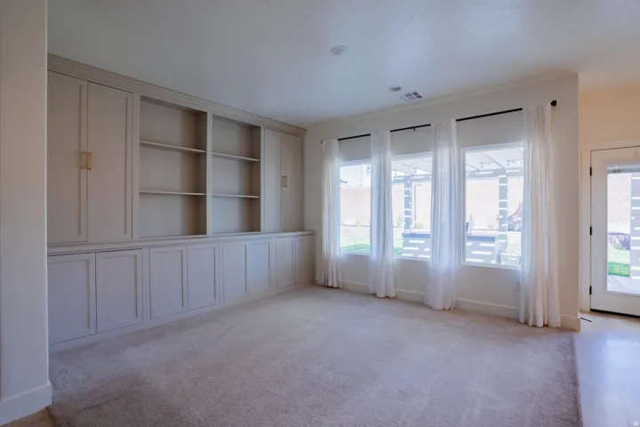 Unfurnished room featuring light carpet and built in shelves