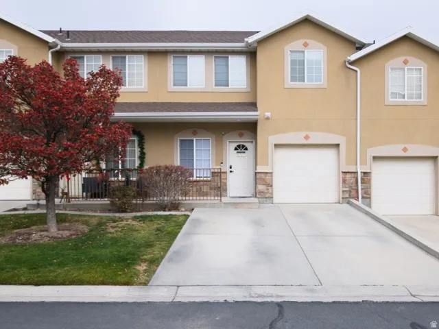 Traditional home featuring stucco siding, driveway, and stone siding