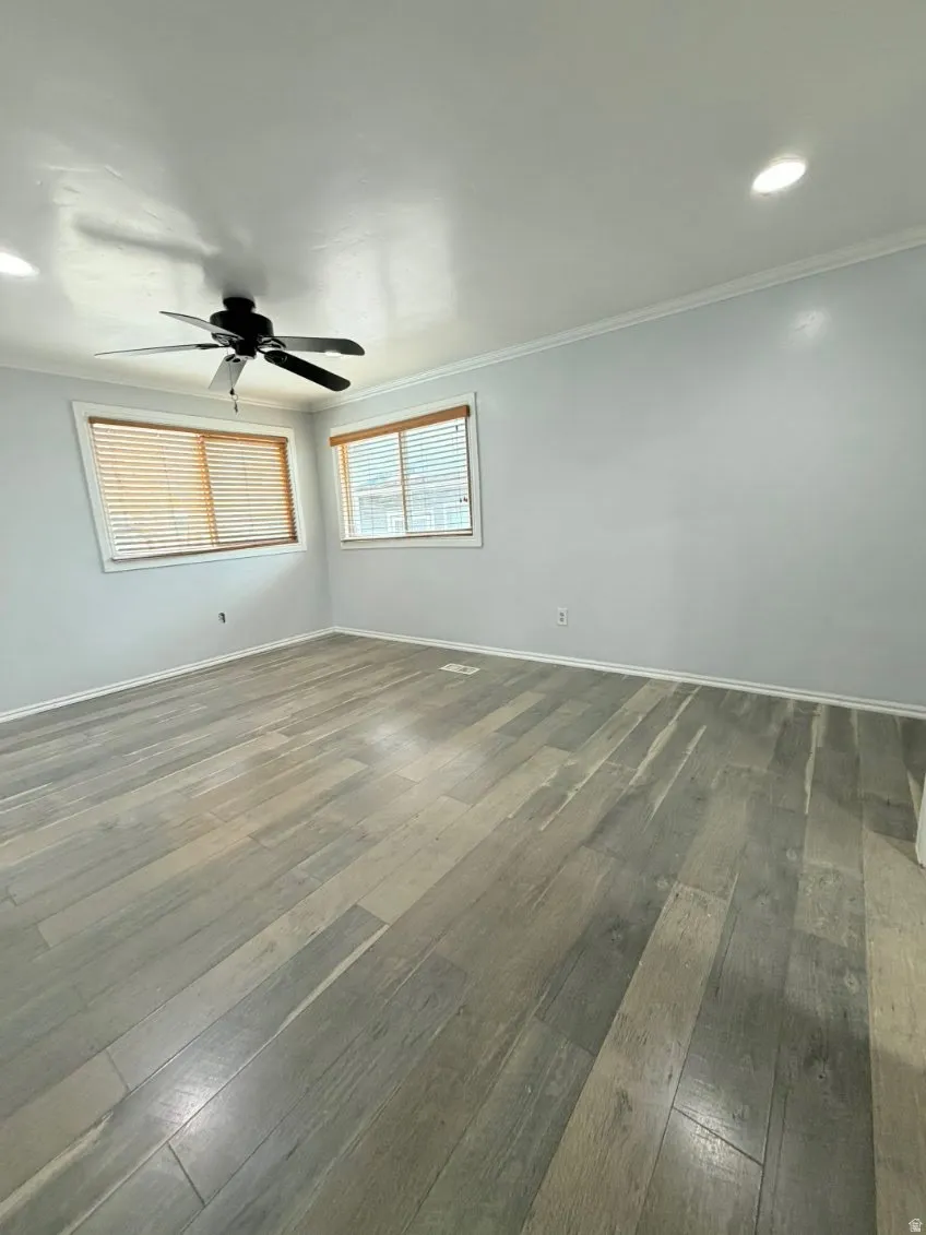 Spare room with dark wood-style flooring, crown molding, ceiling fan, and recessed lighting