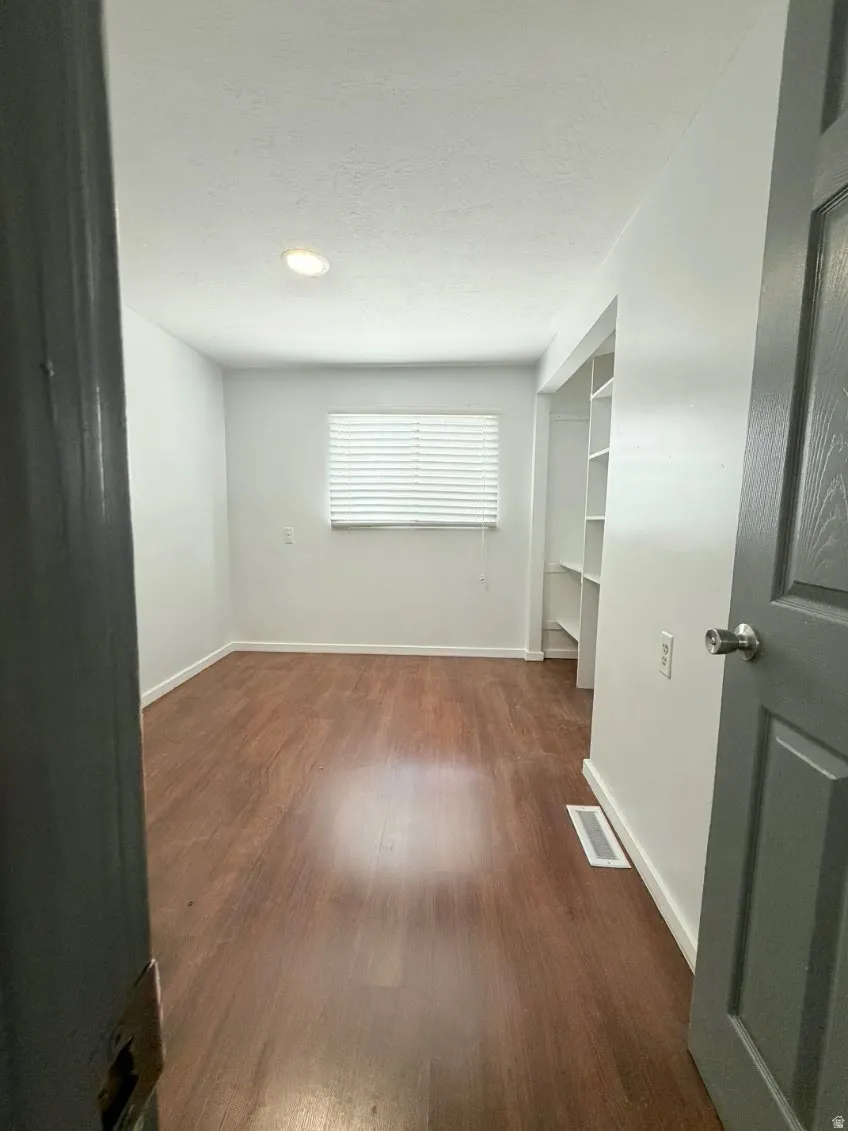 Unfurnished room featuring dark wood-type flooring and a textured ceiling