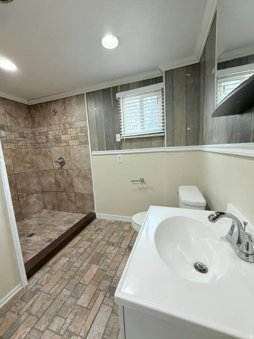 Full bath with brick patterned flooring, a stall shower, vanity, and ornamental molding