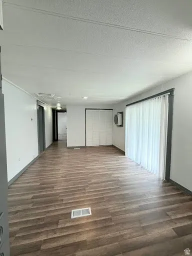 Unfurnished living room featuring dark wood-style floors and baseboards