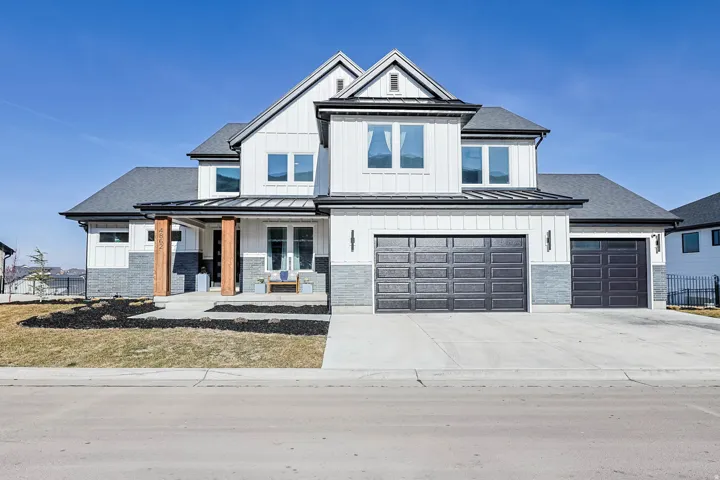 Modern farmhouse with covered porch, board and batten siding, driveway, a standing seam roof, and a metal roof