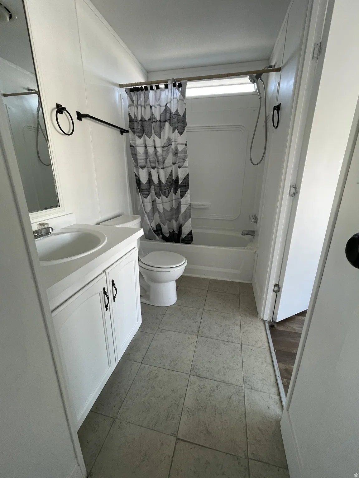 Full bathroom with vanity, shower / bath combo with shower curtain, and light tile patterned floors
