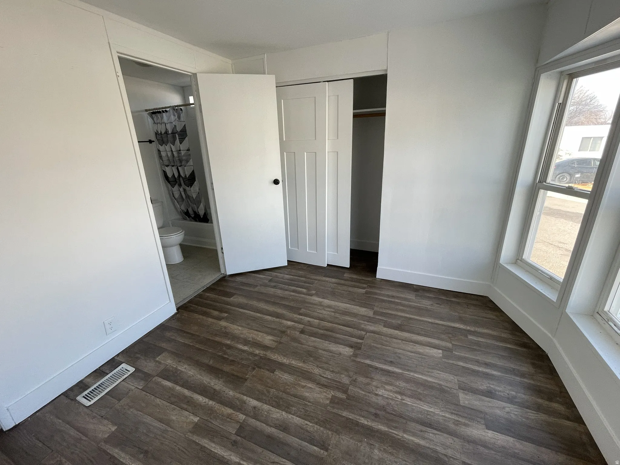 Unfurnished bedroom with dark wood-type flooring, a closet, and connected bathroom
