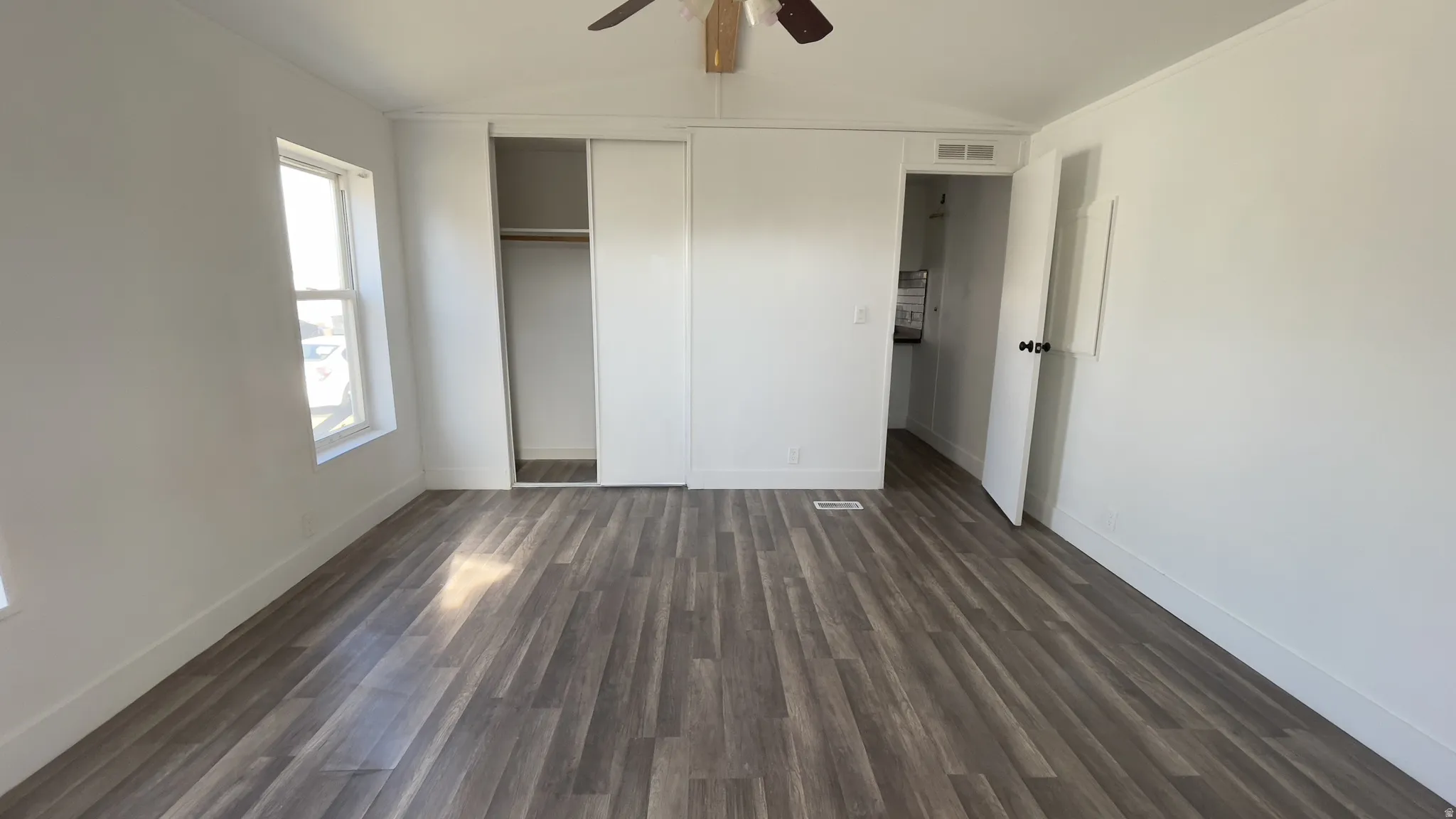 Unfurnished bedroom with vaulted ceiling, dark wood-style flooring, a closet, and ceiling fan