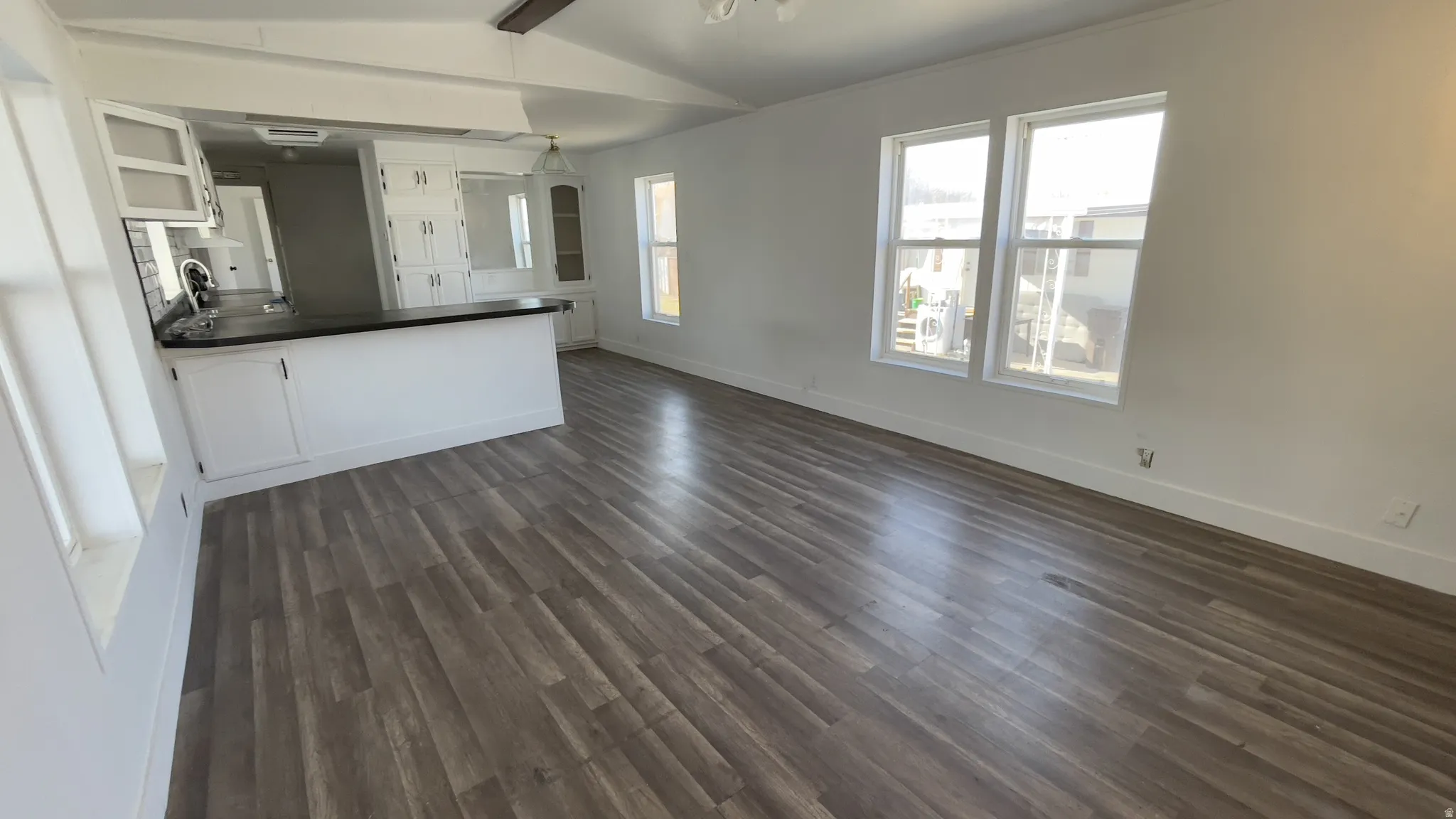 Unfurnished living room with dark wood-style floors and baseboards