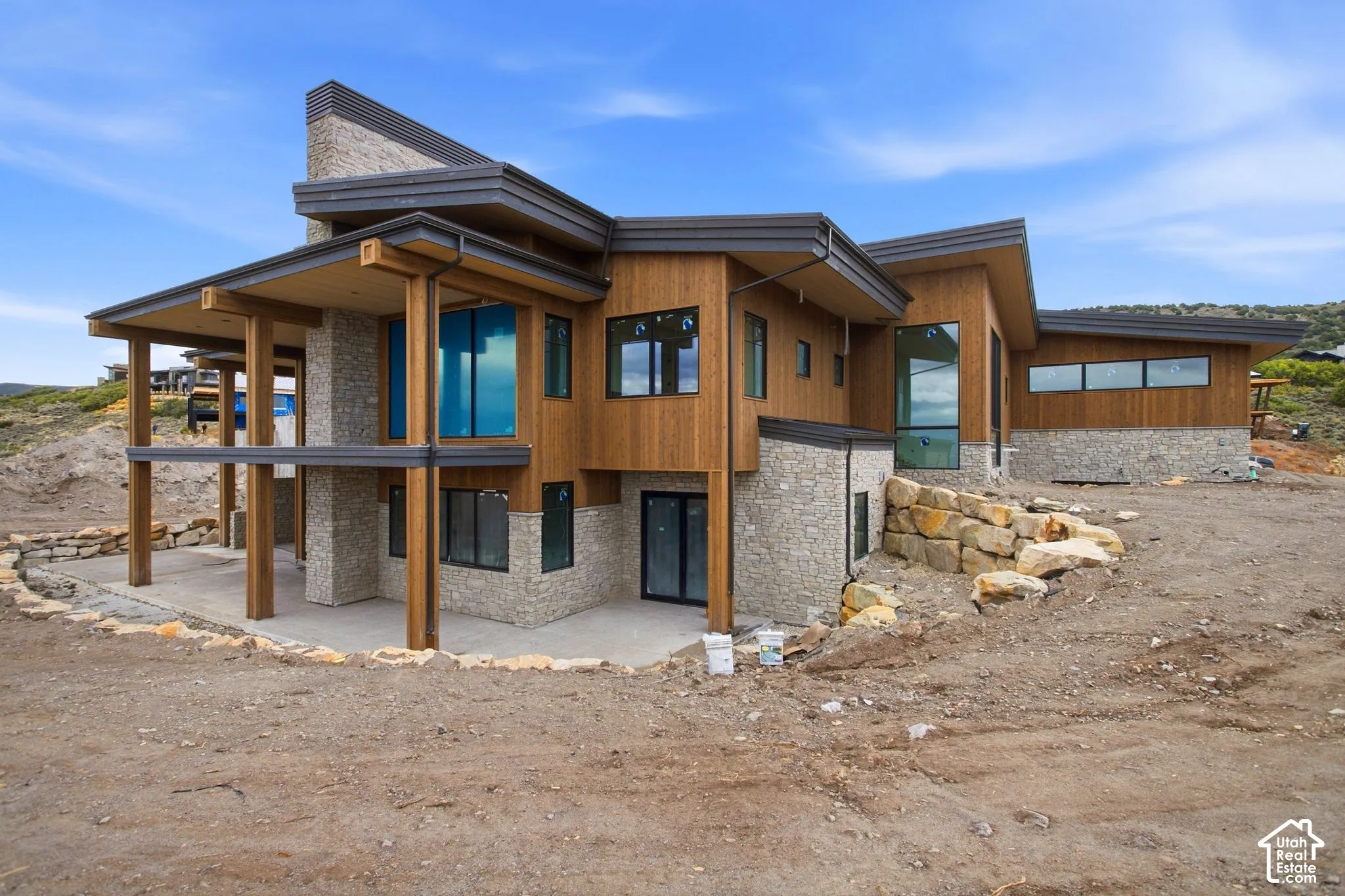 Modern architectural design featuring varied rooflines, wood-finish siding, and stone cladding