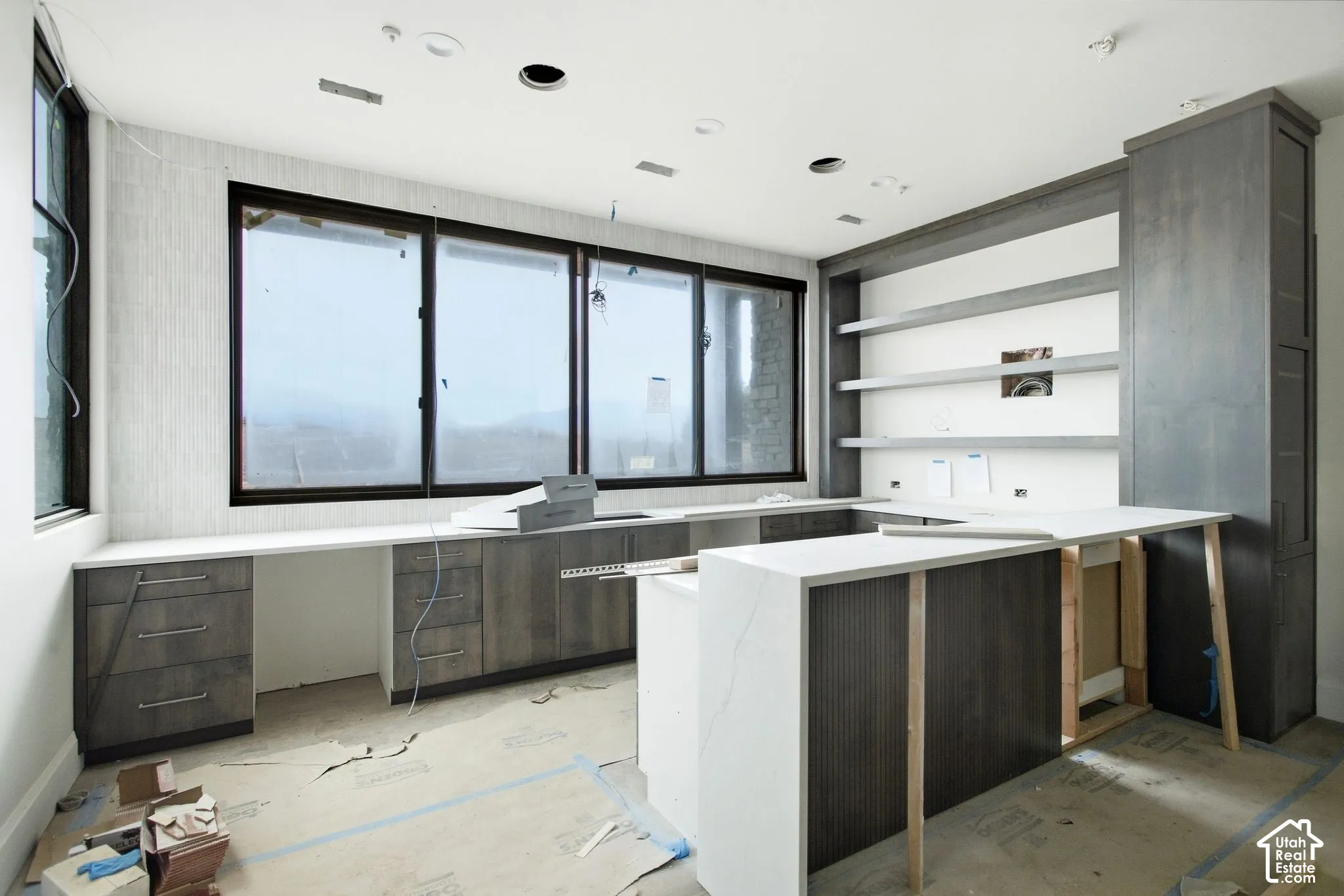 Built-in cabinetry with integrated shelving, expansive windows, light-toned countertops, and recessed lighting