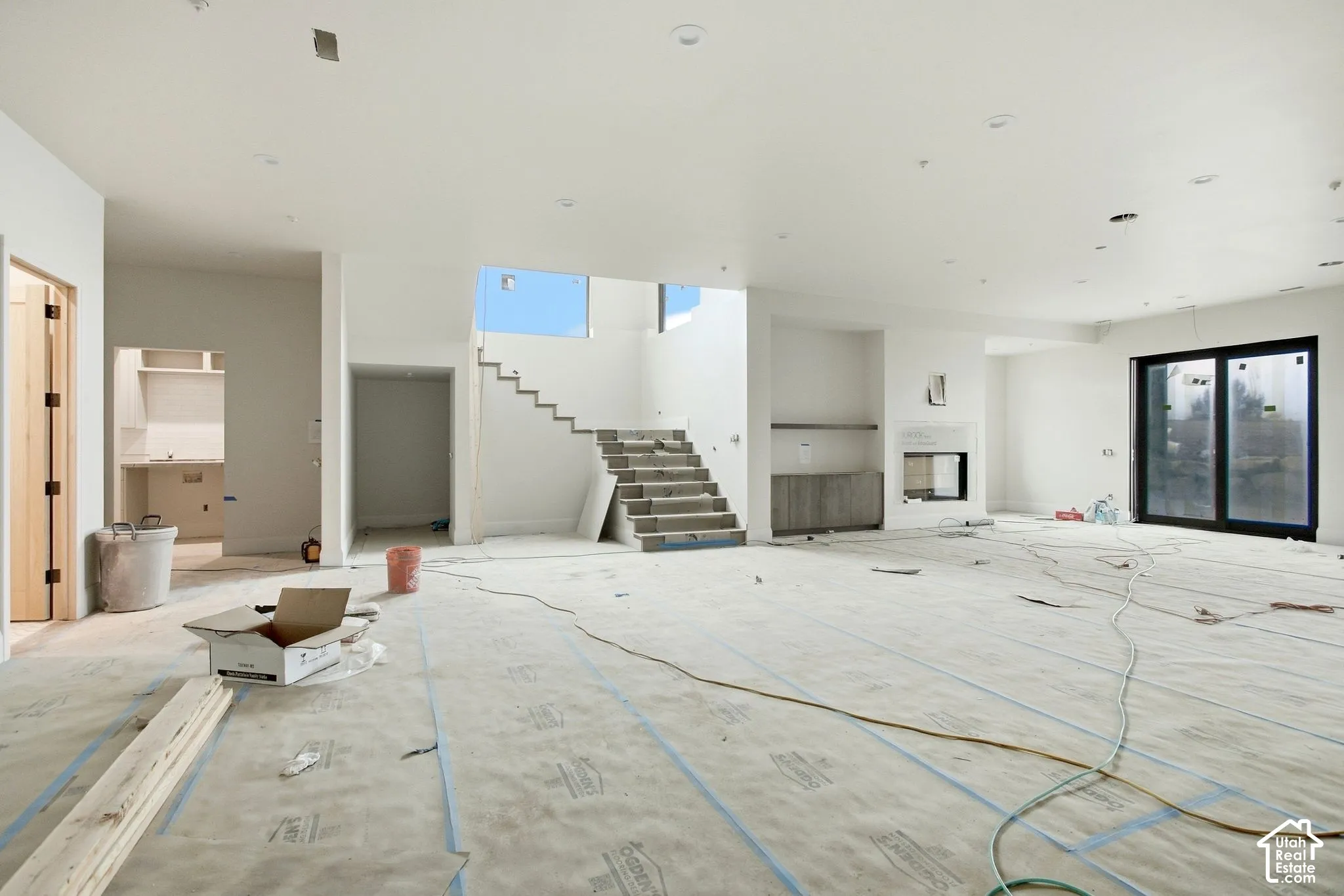 Spacious interior featuring a contemporary fireplace, built-in cabinetry, large sliding glass door, and an open staircase with a partial glass railing
