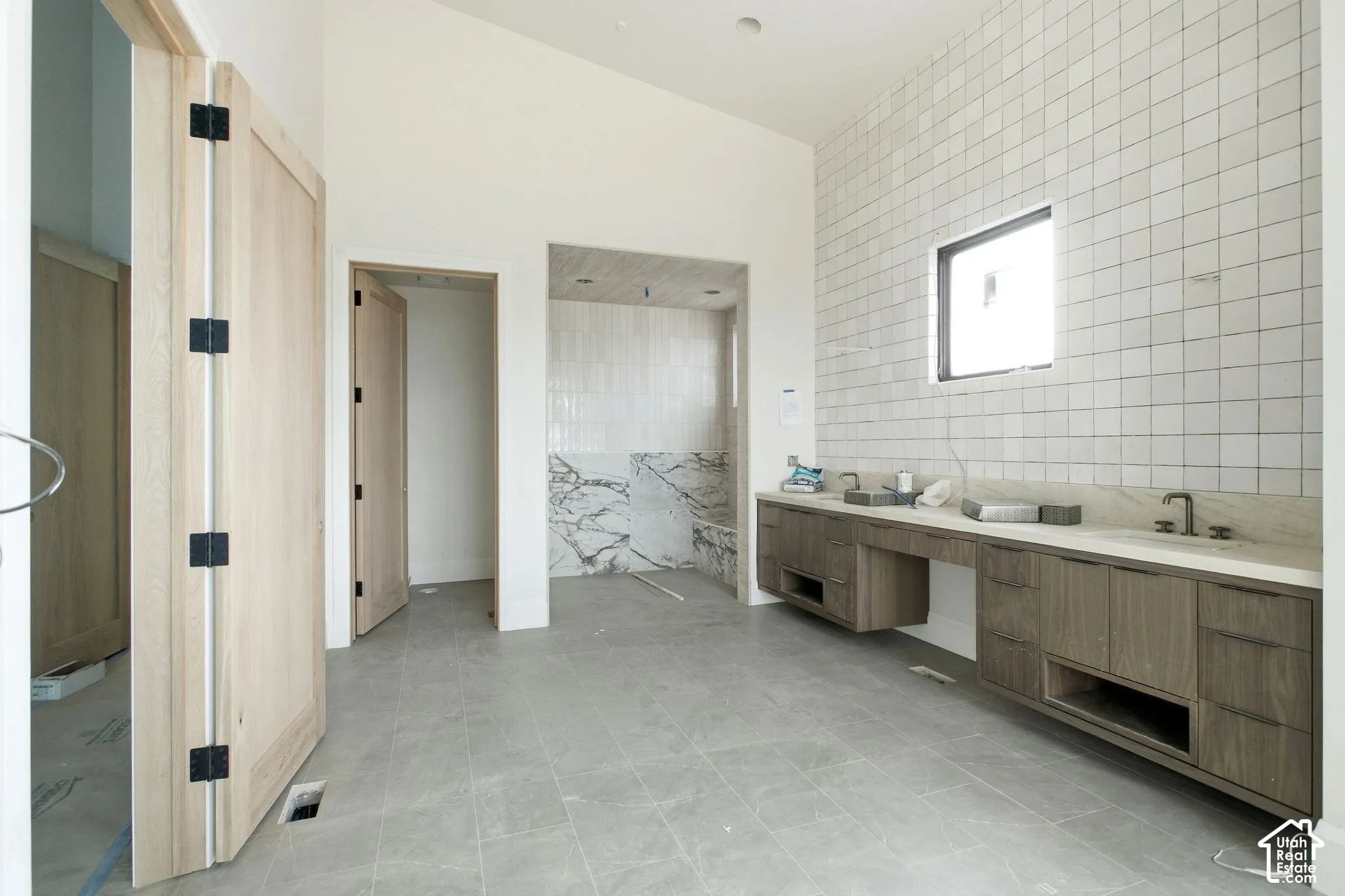 Dual wood-finish floating vanities with integrated sinks, light-toned countertop, and rectangular window