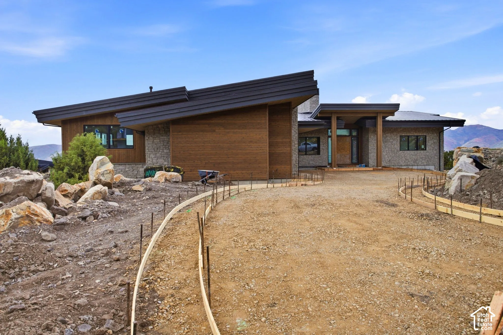 Contemporary exterior featuring wood-finish siding, stone accents, and a distinctive sloped roofline