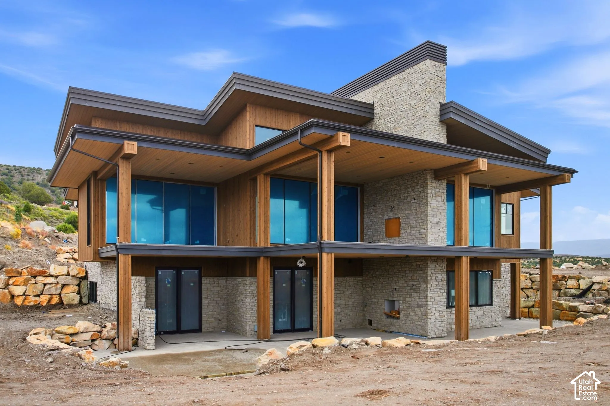 Modern exterior architecture featuring a stone and wood-finish facade, multiple covered balconies, and extensive glass doors