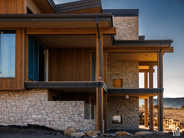 Multi-level exterior featuring natural stone veneer, vertical wood siding, expansive covered balconies, and steel structural supports