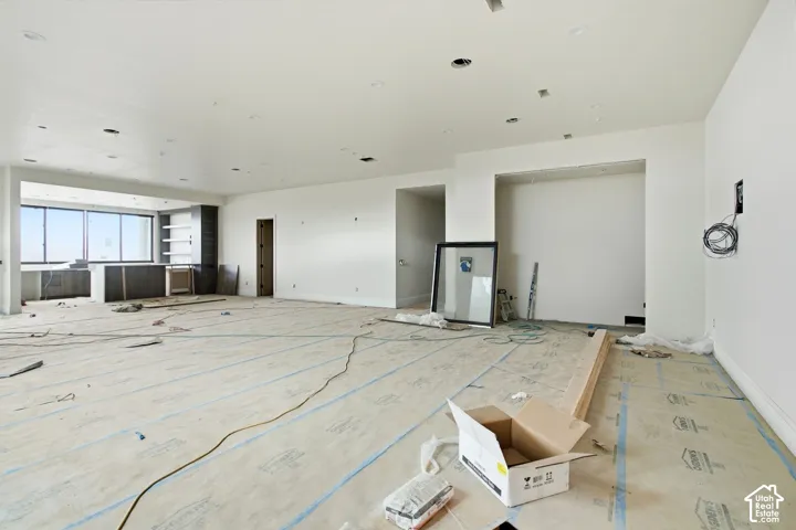 Expansive open-concept space featuring recessed lighting, a built-in cabinetry area with shelving, and large windows