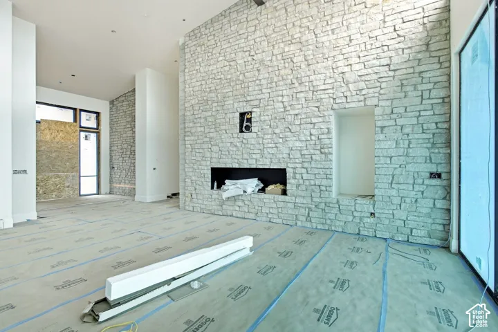 Stone accent wall with built-in fireplace, recessed alcove, and high ceilings