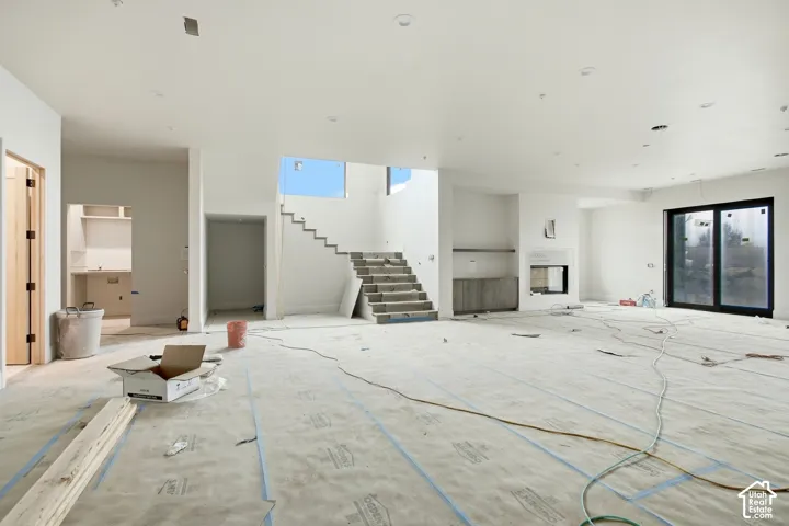 Spacious interior featuring a contemporary fireplace, built-in cabinetry, large sliding glass door, and an open staircase with a partial glass railing
