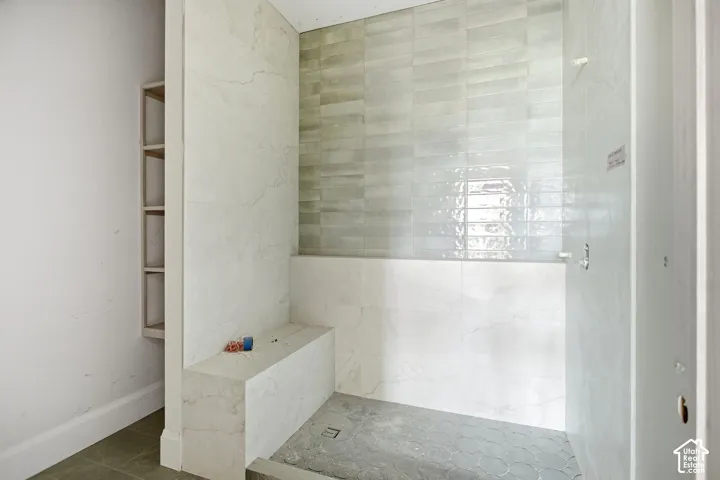 Shower with a built-in bench, tiled walls, and a tiled floor