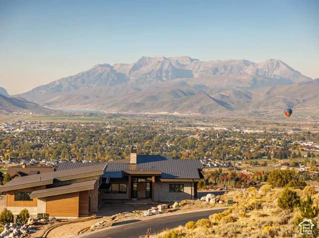 Contemporary residence featuring a multi-pitched metal roof, horizontal wood-finish siding, stone exterior masonry, and an elevated position overlooking a mountain range