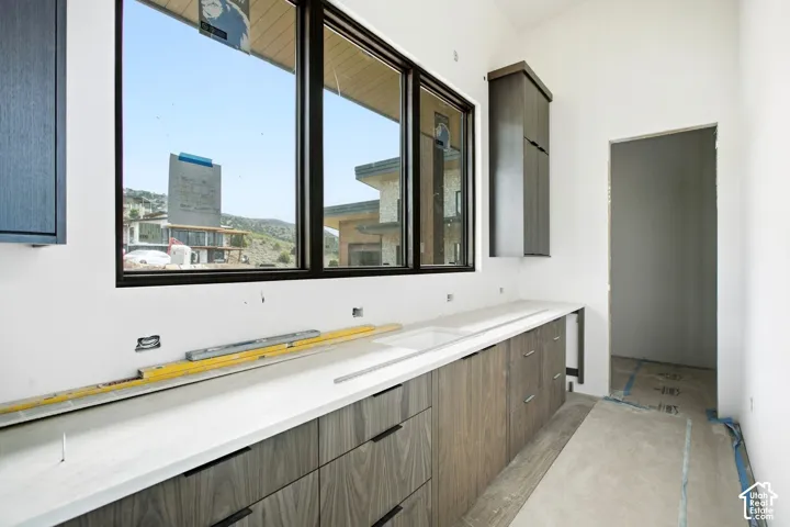 Window with dark trim, light countertop with an integrated sink, and wood-finish cabinetry