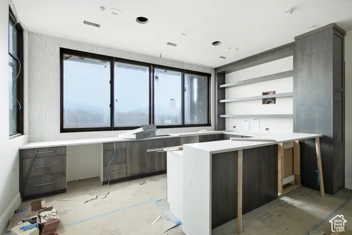 Built-in cabinetry with integrated shelving, expansive windows, light-toned countertops, and recessed lighting