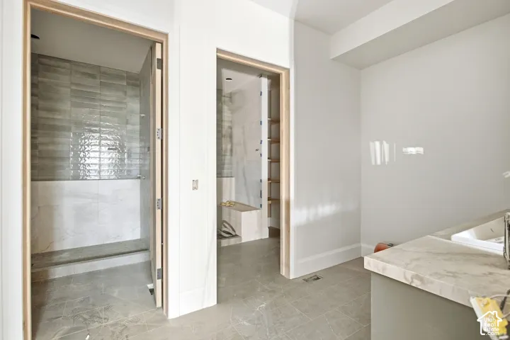 Walk-in shower with large format and subway tile, wood-finish door frames, and stone-look flooring