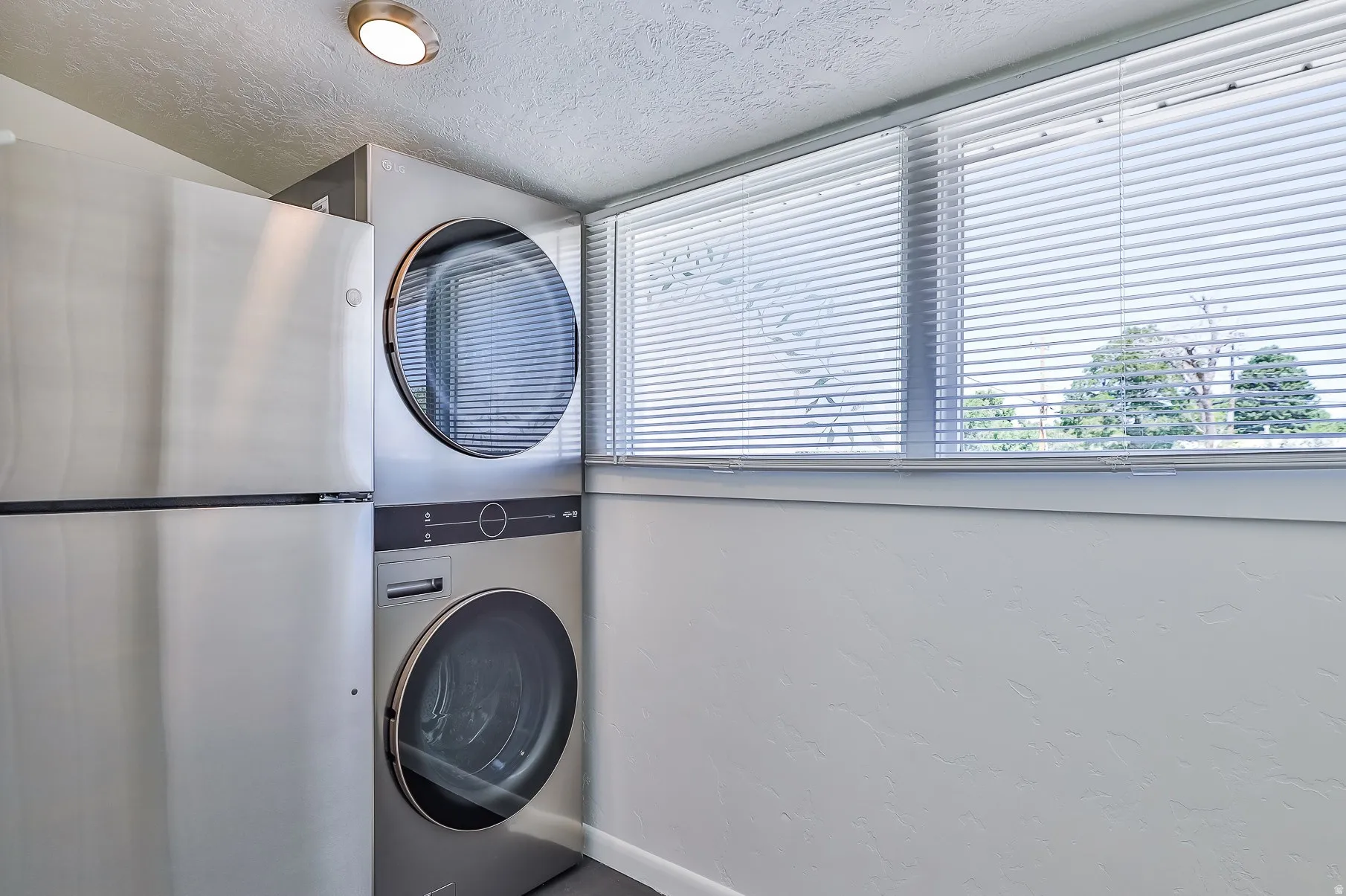Washroom with stacked washer and clothes dryer and a textured ceiling