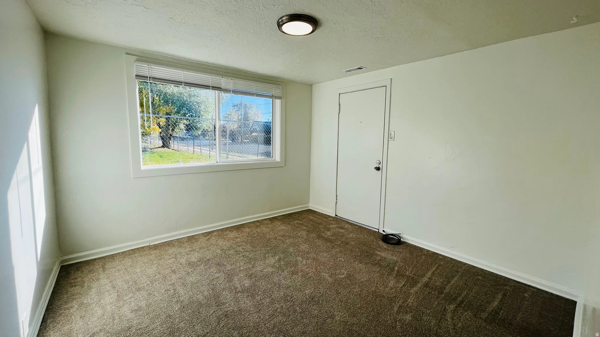 Empty room featuring a textured ceiling and carpet flooring
