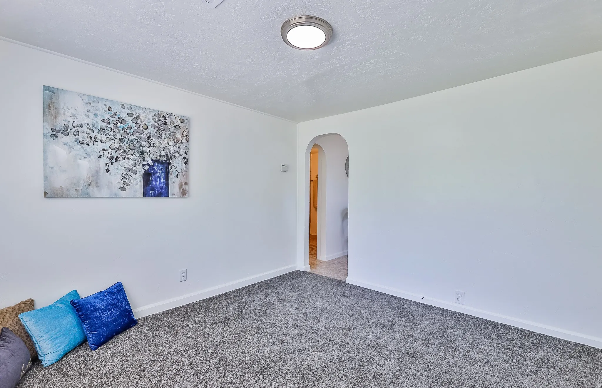 Empty room with arched walkways, a textured ceiling, and carpet