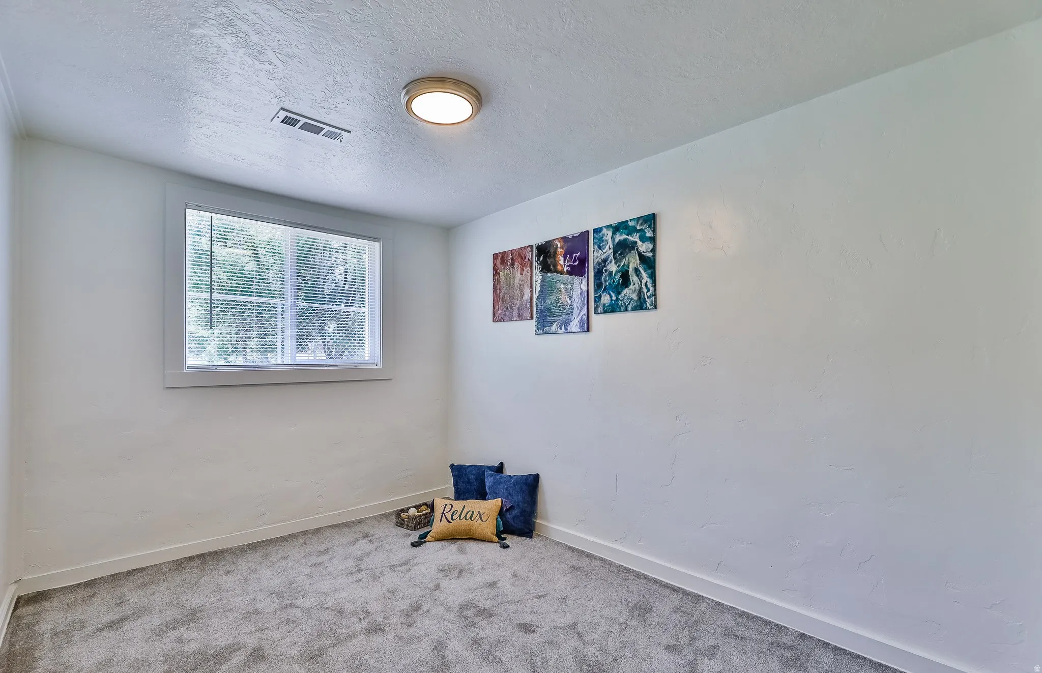 Carpeted empty room featuring a textured ceiling and baseboards