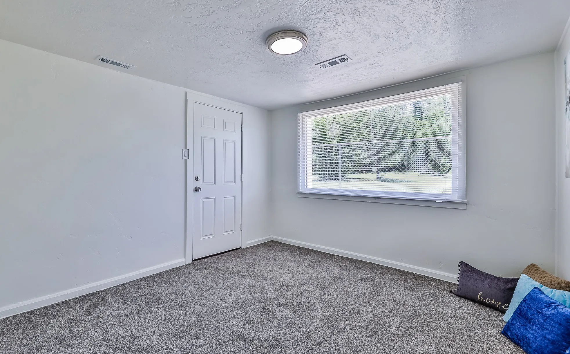Carpeted spare room with a textured ceiling and baseboards