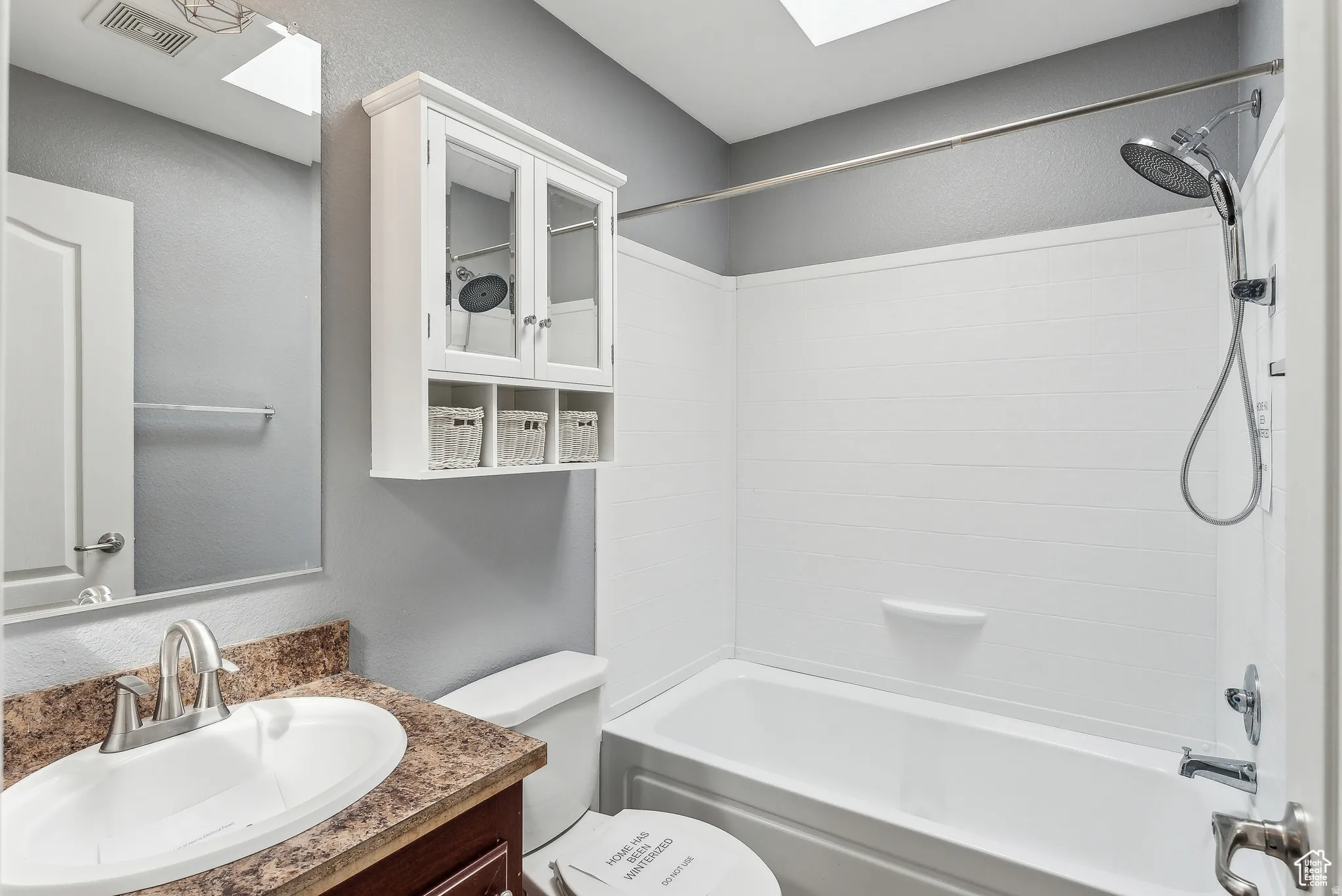 Full bathroom featuring tub / shower combination, a skylight, vanity, and a textured wall