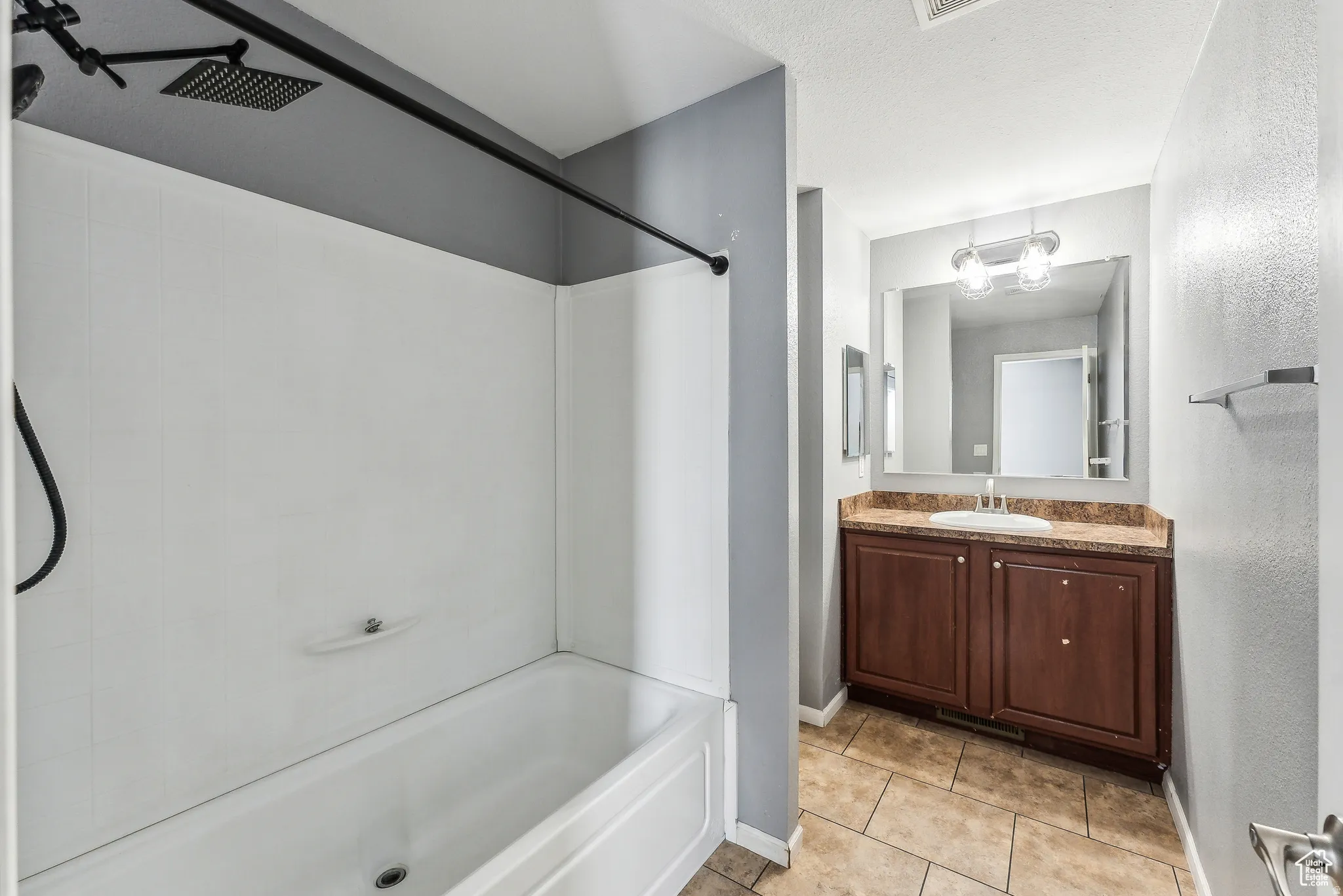 Bathroom with shower / tub combination, vanity, light tile patterned floors, and a textured ceiling