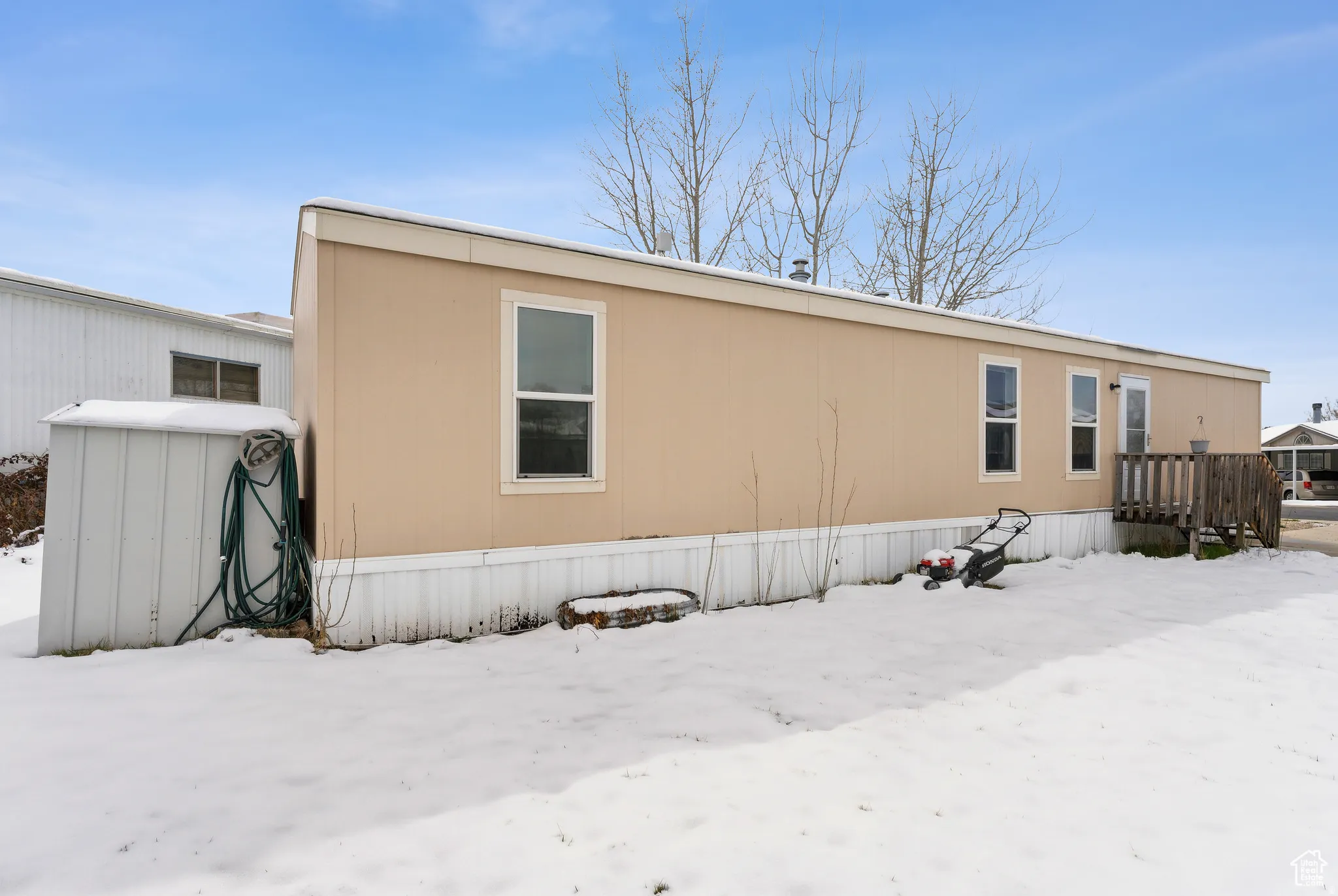 Snow covered back of property with a wooden deck