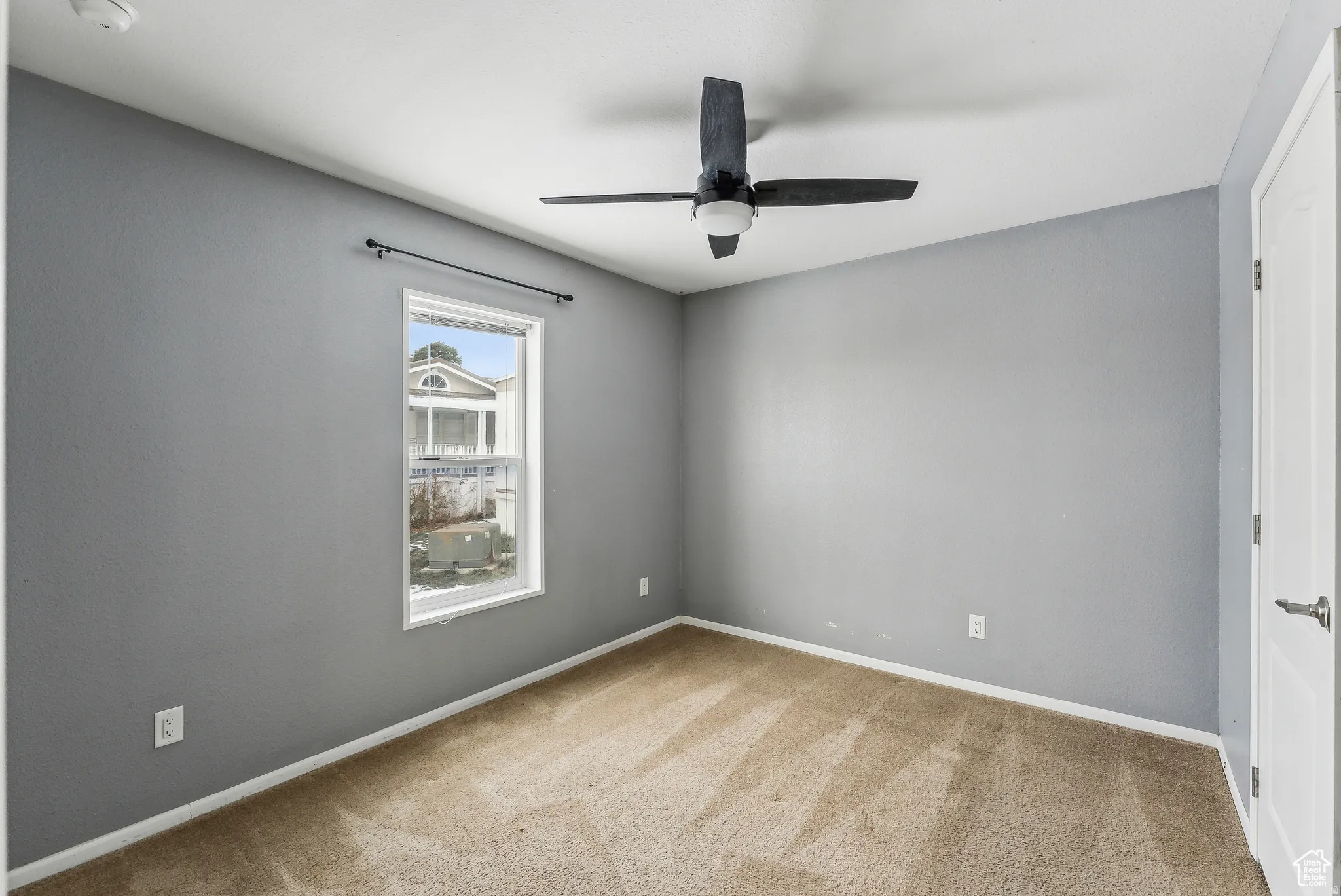 Empty room featuring light carpet and a ceiling fan