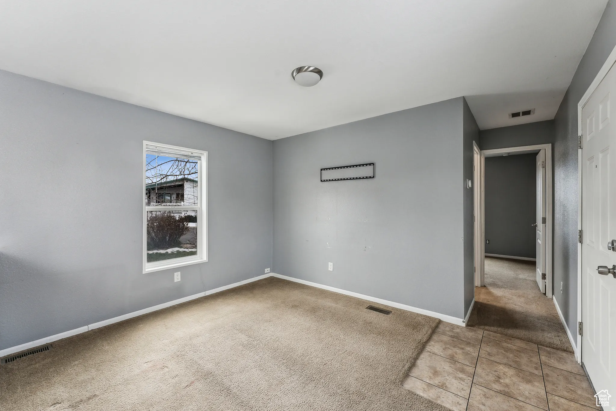 Empty room featuring light colored carpet and light tile patterned flooring