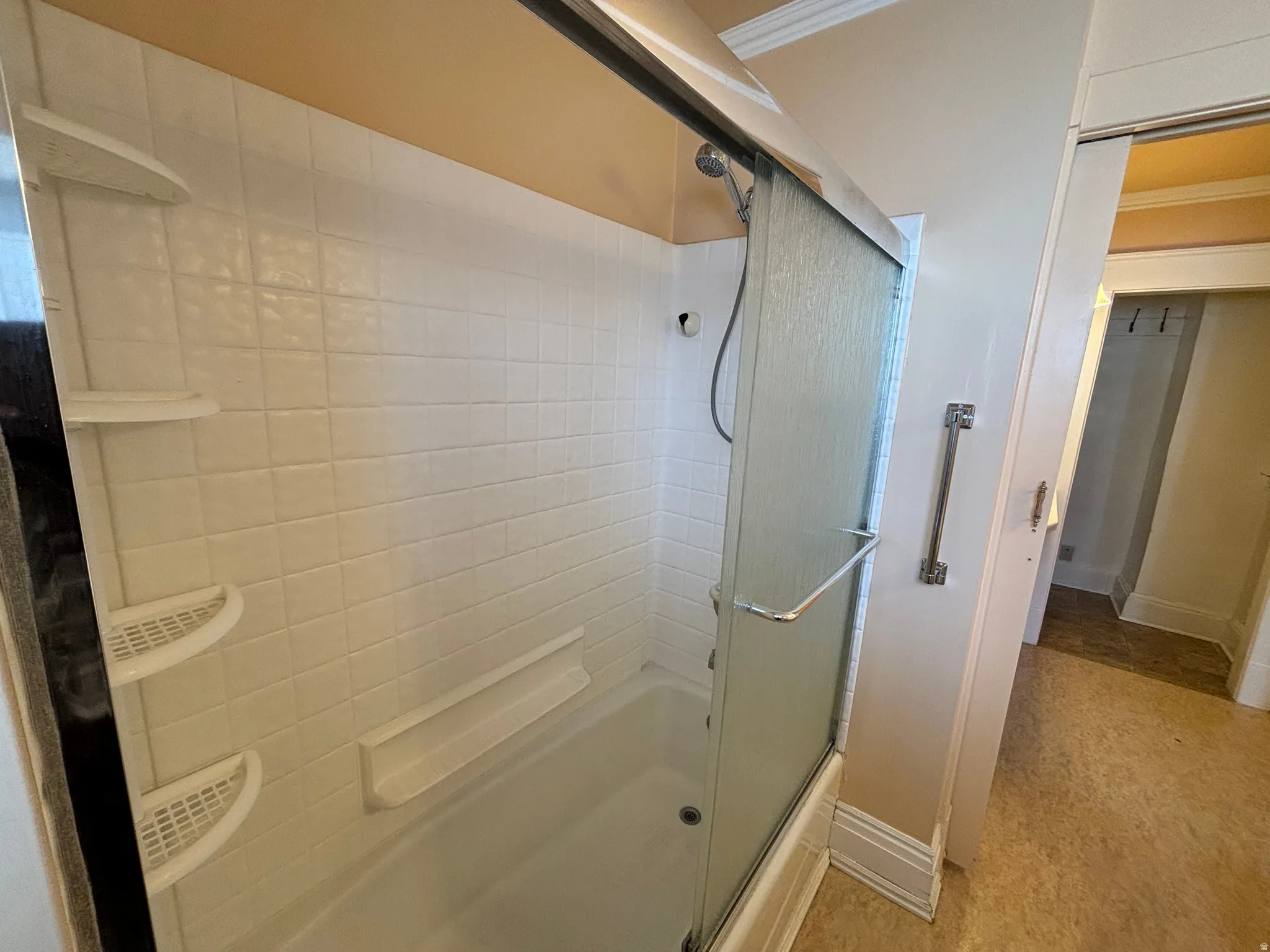 Bathroom with combined bath / shower with glass door and crown molding