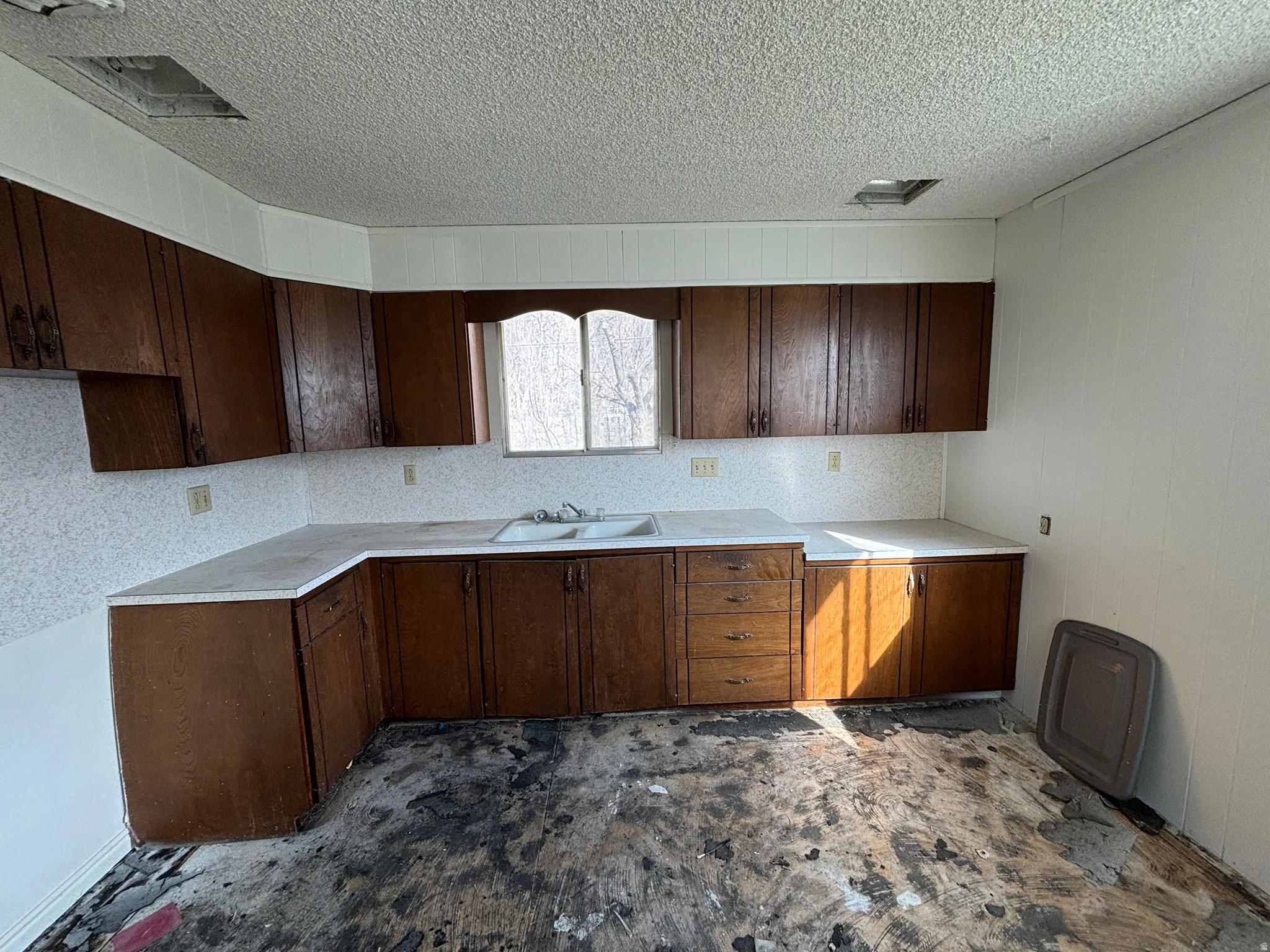 Kitchen with dark wood finish cabinetry, light countertops, and a textured ceiling