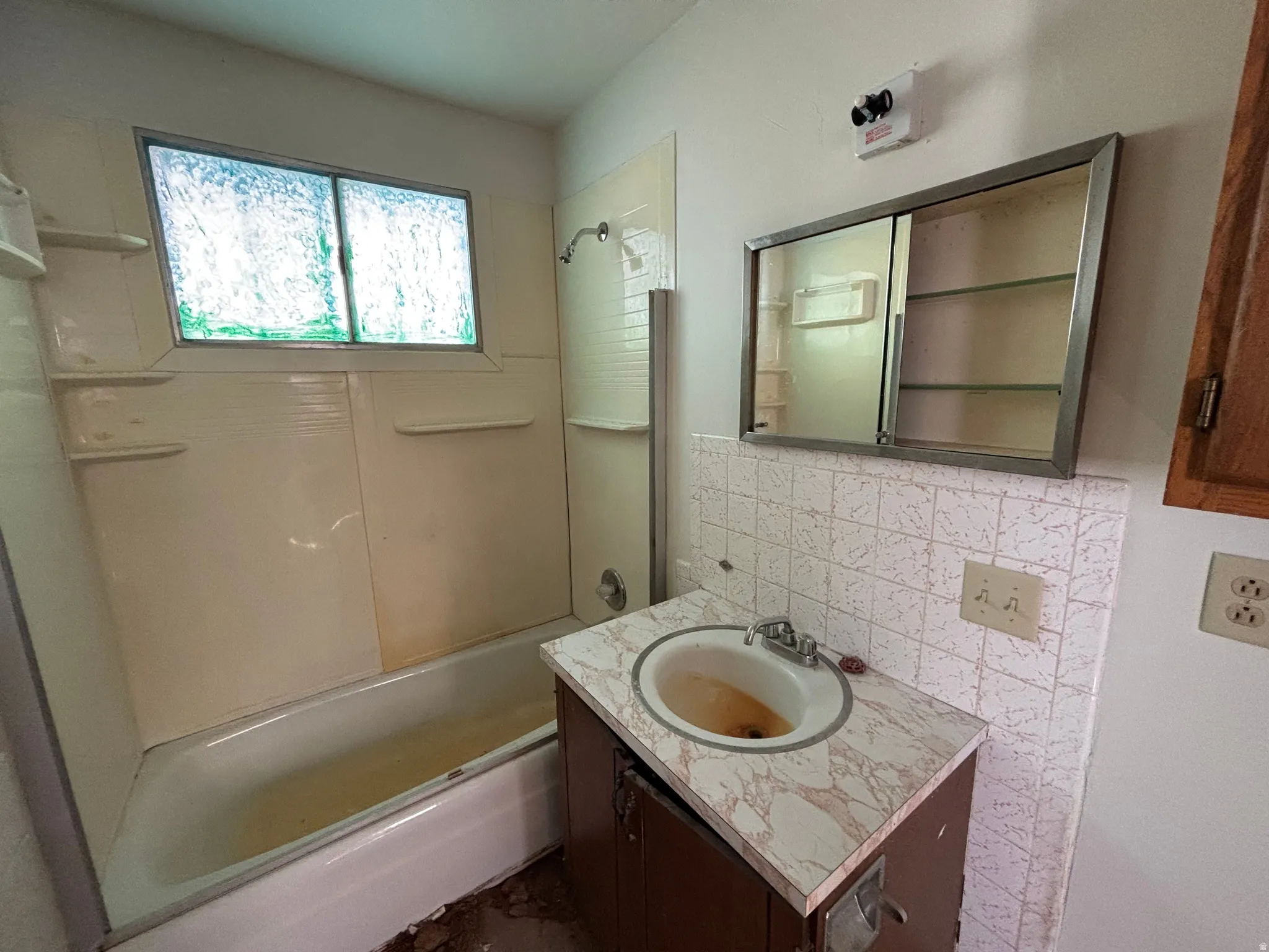 Bathroom with vanity, shower / washtub combination, and backsplash