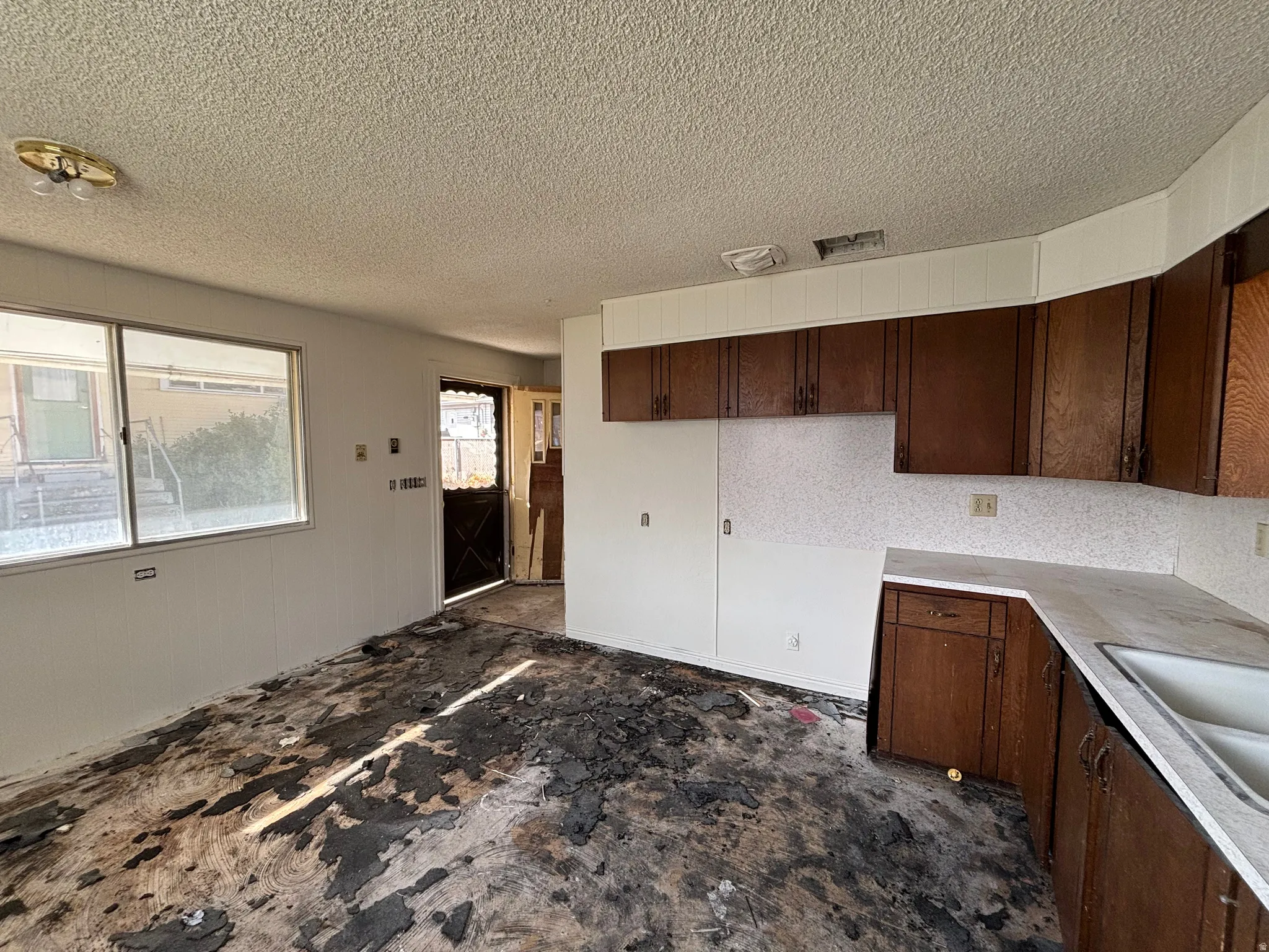 Kitchen with dark wood finish cabinetry, light countertops, and a textured ceiling