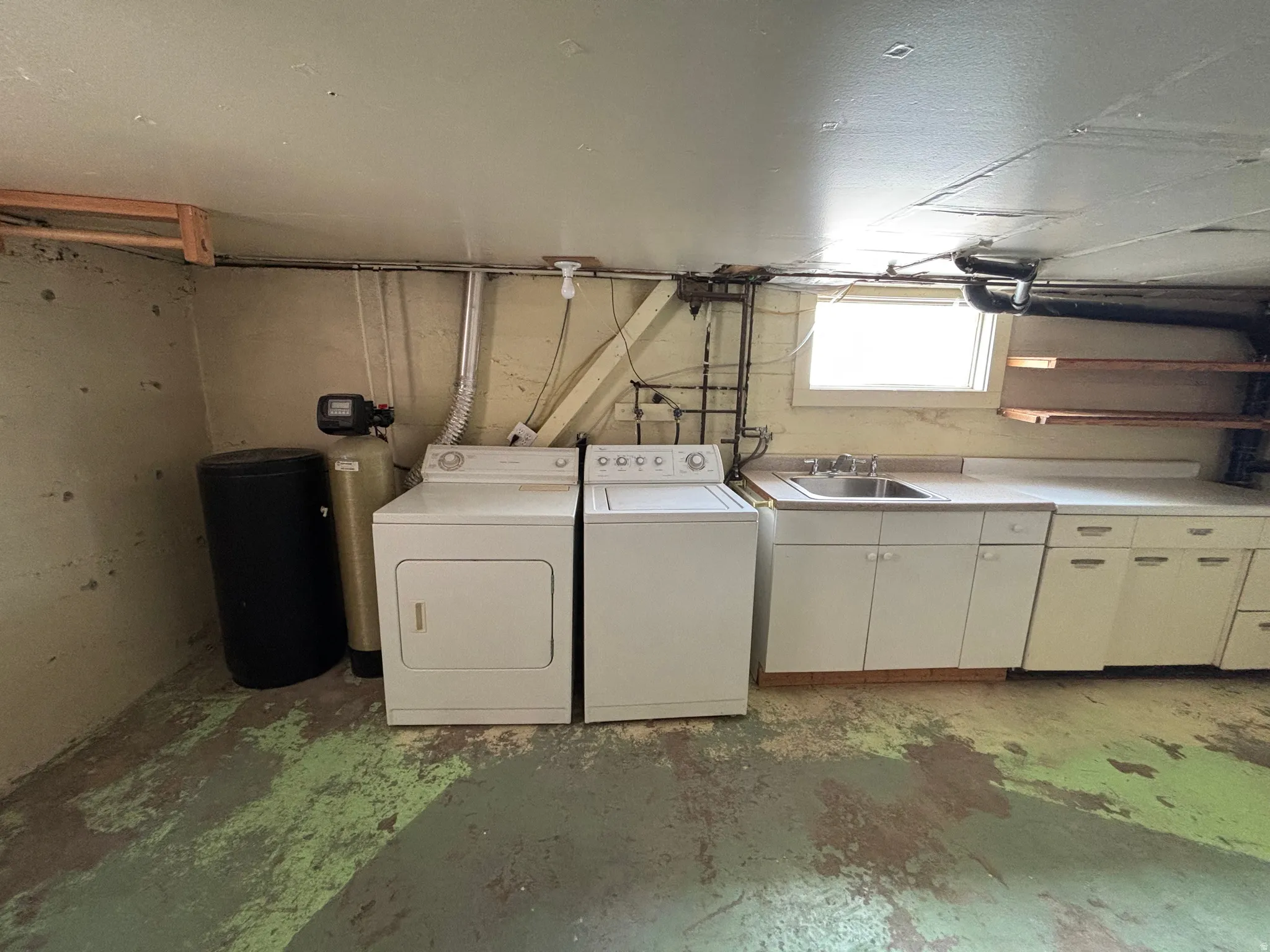 Laundry room with unfinished concrete flooring and washing machine and dryer